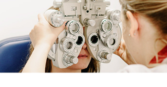 Ihr Optiker vor Ort passt Ihnen gerne Gleitsichtkontaktlinsen an. Eine Frau beim Optiker zum Sehtest.
